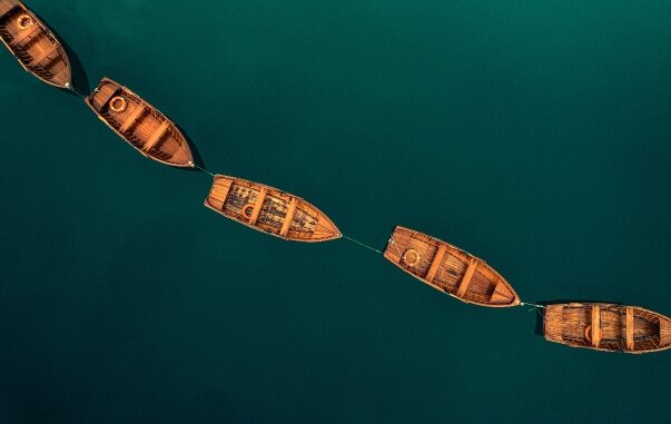 Wooden boats floating in a line on deep teal water