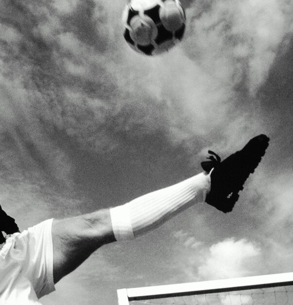 Football player kicking a ball mid-air